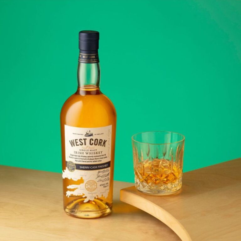 Beautyshot de la bouteille de West Cork Single Malt Irish Whiskey finition Sherry Cask, accompagnée d’un verre de dégustation, sur fond vert, mise en avant d’un whisky irlandais fruité et élégant.