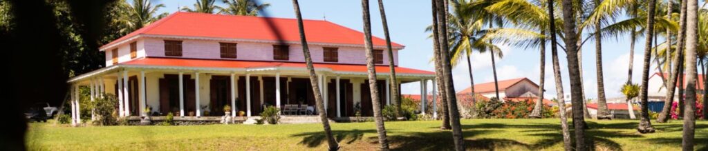 Image de la page marque de rhum agricole Longueteau sur le site Le Club des Connaisseurs : Habitation créole traditionnelle entourée de palmiers en Guadeloupe, domaine du Marquisat de Sainte-Marie.