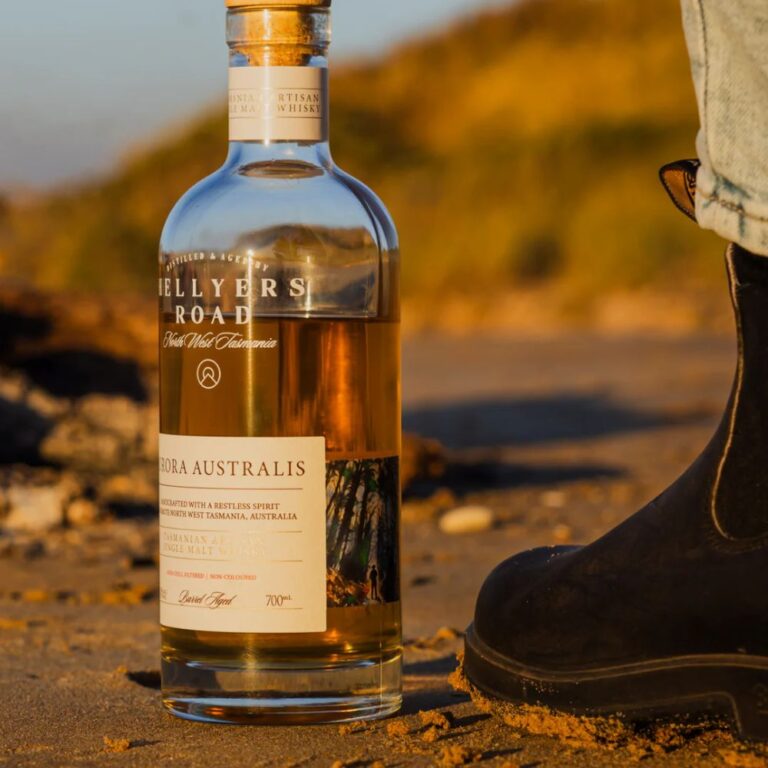 Photo sur la plage du whisky single malt Hellyers Road Aurora Australis avec des chaussures noires sur le coté
