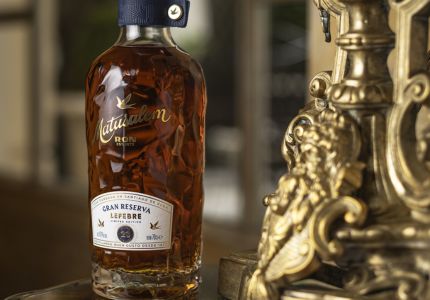 Bouteille de rhum Matusalem Gran Reserva Leyenda posée sur une table élégante, avec en premier plan un ornement doré de style baroque.